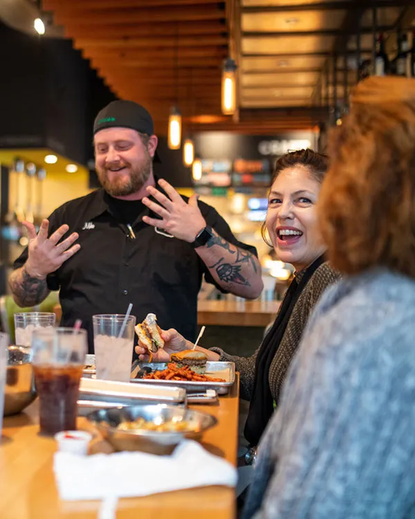 Hopdoddy customers at table laughing with server 